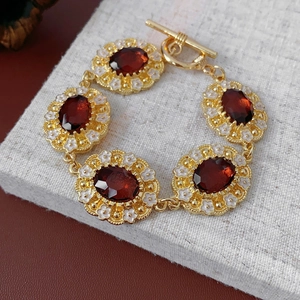 Close-up of vintage gold bracelet with oval brown stones and white floral accents