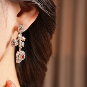 Detail of vintage flower earrings with red gems and zircons worn on a female model