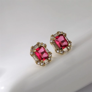 Detail of gold earrings with a red rectangular gemstone and white accent stones