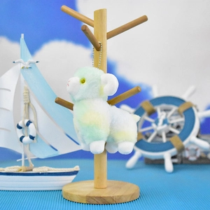 Detailed shot of a cute pastel plush sheep keychain hanging on a wooden stand