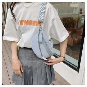 Detail of light blue crescent bag with woven strap and decorative pearl chain