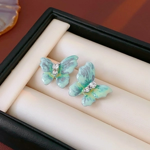 Détail macro de boucles d'oreilles papillon en émail vert vintage avec cristaux étincelants
