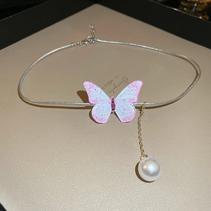 Détail du pendentif papillon rose avec chaîne serpent argentée et accent de perle blanche