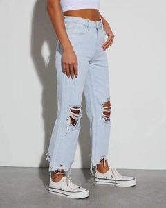 Dettaglio jeans denim azzurro a vita alta con ginocchia strappate e orli a taglio vivo
