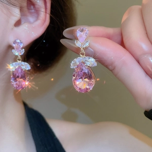 Détail de boucles d'oreilles dorées avec zircon goutte rose et pierres taille marquise