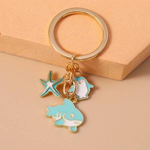 Detail of gold keychain featuring blue enamel starfish, penguin, and shark charms