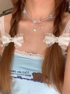 Detailed view of layered flower bead necklace and lace bow hair clips with heart crystals