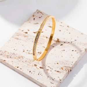 Dettaglio del bracciale in acciaio al titanio dorato con zirconi su base in pietra