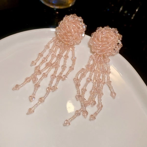 Detailed view of pink crystal beaded fringe earrings with flower ball studs on a plate