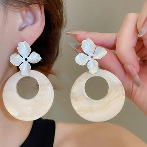 Detailed view of cream marble resin ring earrings with silver floral stud accents