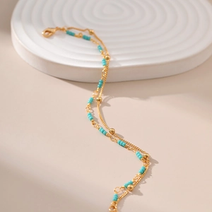 Detail of double-layer 18K gold plated bracelet featuring turquoise beads and lobster clasp