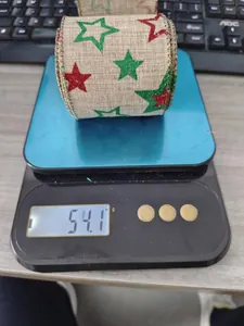 Close-up of burlap Christmas ribbon with red and green glitter stars on a digital scale