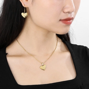 Gros plan d'un ensemble de bijoux coeur doré avec collier et boucles sur un mannequin