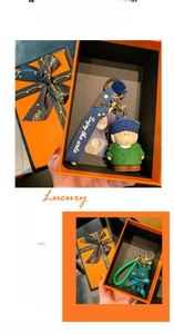 Luxury orange gift box with Van Gogh character and green woven bear keychains and black ribbon