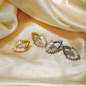 Elegant gold and silver teardrop zircon stud earrings on yellow silk fabric background
