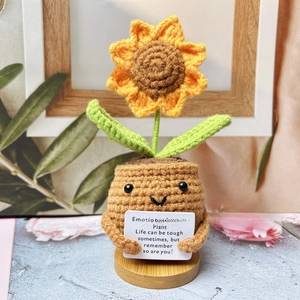Macro detail of handmade crochet sunflower pot with smiling face and support card