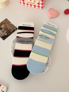 Macro detail of striped mid-calf cotton socks in premium frosted paper packaging
