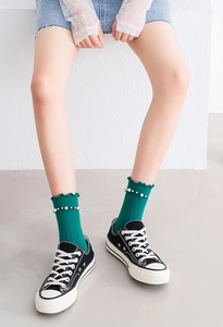 Detailed close-up of green cotton socks featuring elegant pearl accents and ruffled edges