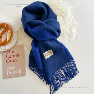 Detail of royal blue cashmere scarf featuring long fringe and a minimalist brand label
