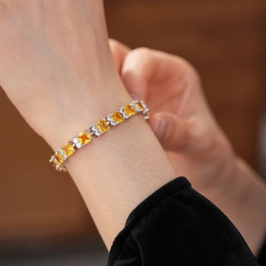 Primer plano de pulsera con circonitas amarillas cuadradas en la muñeca con plata