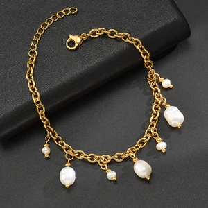 Detail of gold link chain bracelet with baroque pearls on black leather background