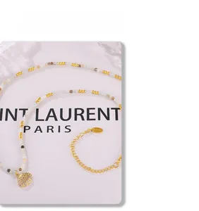 Detail of beaded necklace with gold shell pendant and stainless steel clasp and tag