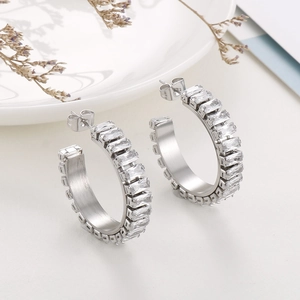 Detailed view of silver C-shape earrings with baguette-cut white zircon inlays