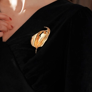 Polished gold irregular leaf brooch shown pinned on elegant black velvet fabric