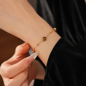 Gold plated bracelet with tiger eye stone and round beads worn on a wrist