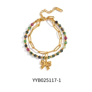 Detail of layered stainless steel bracelet with golden bow pendant and colorful beads
