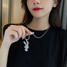 Detail of silver snake chain necklace with sparkling rhinestone rabbit pendant on model
