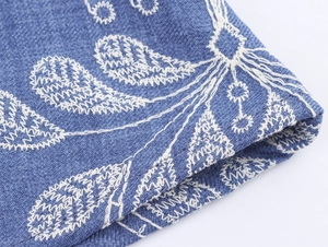 Gros plan détaillé du tissu bleu avec une broderie florale blanche et une texture fine