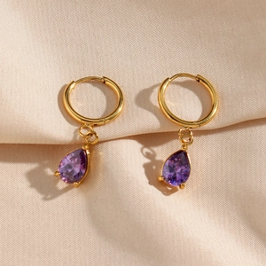 Detalle macro de pendientes de aro de oro 18K con circón de gota púrpura en satén