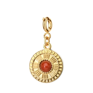 Macro shot of gold stainless steel pendant with round red-orange natural stone setting