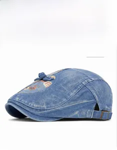Detail der blauen Denim-Baskenmütze mit Blumenstickerei und verstellbarer Metallschnalle
