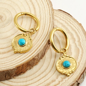 Detail of 18K gold stainless steel earrings with sunburst pattern and turquoise stone