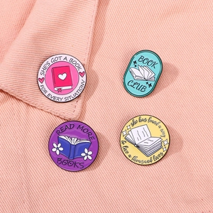 Set of four colorful enamel book club badges featuring reading quotes on pink fabric