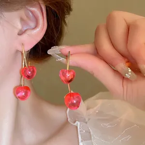 Pink translucent cherry drop earrings in gold finish worn by a model in close-up shot