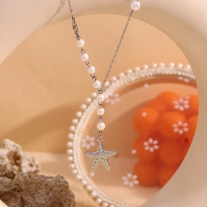 Detailed close-up of textured starfish pendant with white pearls on a silver necklace
