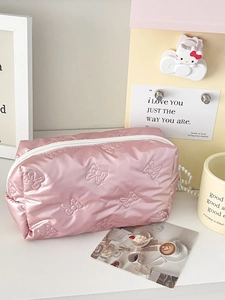 Detail of pink quilted makeup bag featuring 3D bow embossed texture and white zipper closure