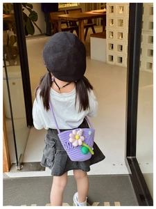 Detail of child wearing a purple knitted crossbody bag with a large floral decoration