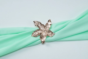 Detailed close-up of golden starfish napkin ring with texture on mint green fabric