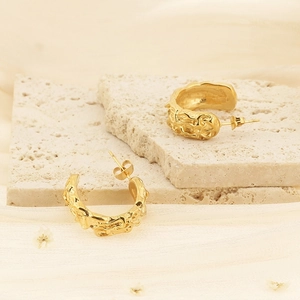 Vintage gold C-shape irregular lava texture earrings on a minimalist stone background