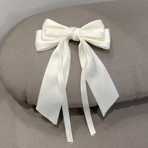 Detail of elegant cream white satin ribbon hair clip with flowing long streamers