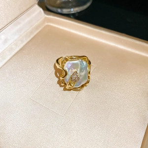 Détail d'une bague perle baroque sur monture feuille dorée avec diamants en coffret