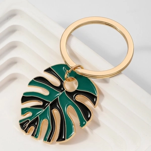 Detail of green and black enamel monstera leaf keychain with golden metal ring