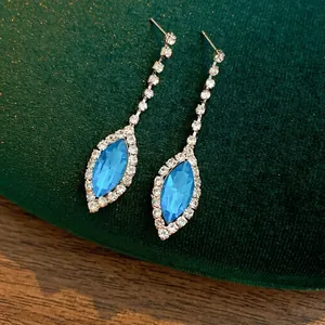Elegant blue teardrop earrings with crystals and tassels on green velvet background