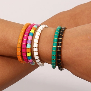 Close-up of stacked colorful enamel bangles with gold trim on model's arm