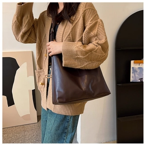 Chic dark brown leather tote bag shown on model in a minimalist interior setting