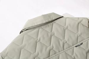 Detail of light gray quilted jacket collar with zigzag stitching and brand neck label